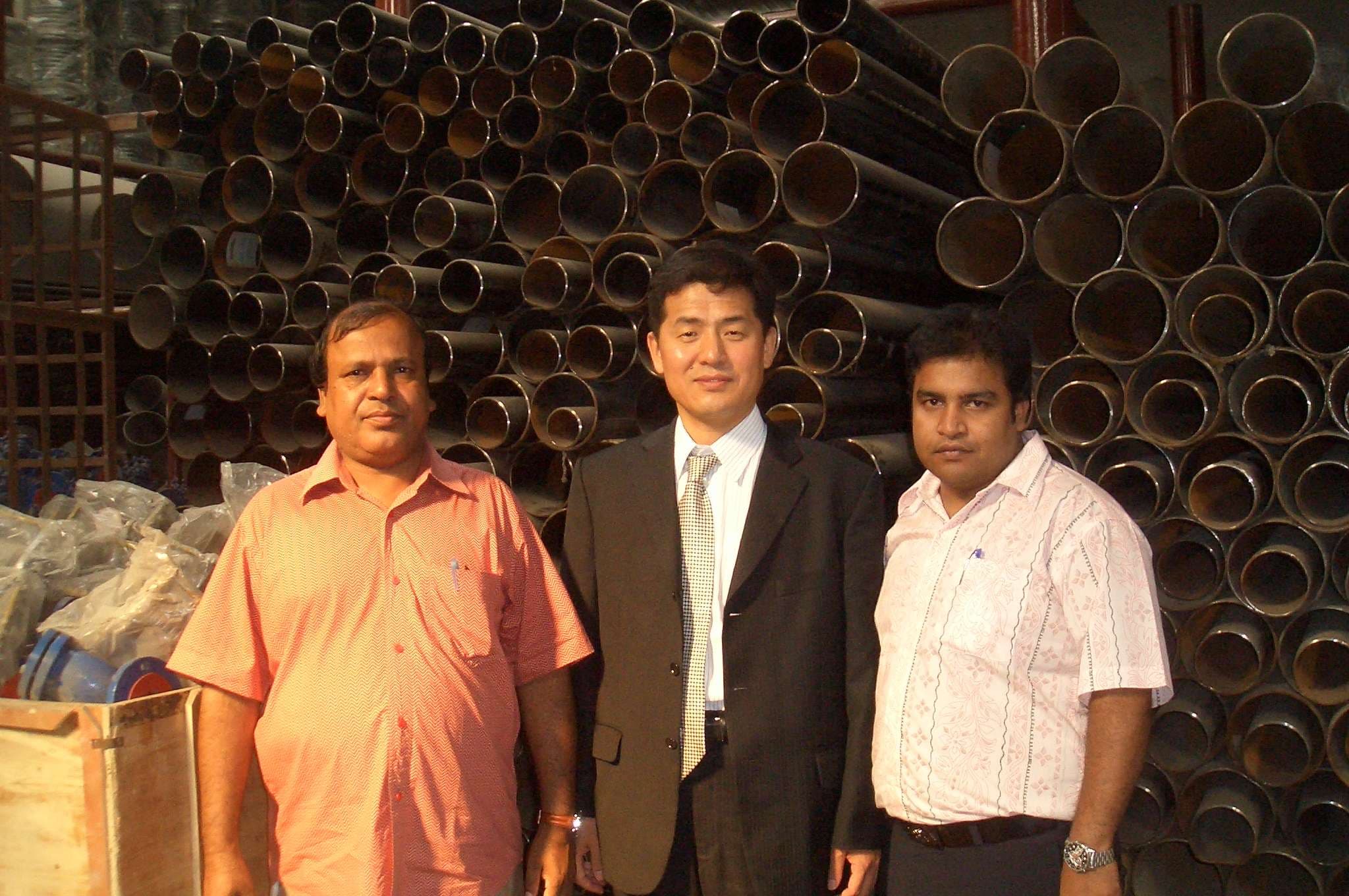 Asgar Trading team with a principal in front of steel pipe stock